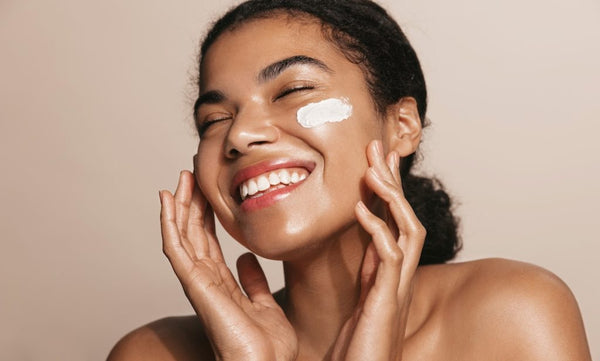 Woman smiling while applying moisturizer to her cheek