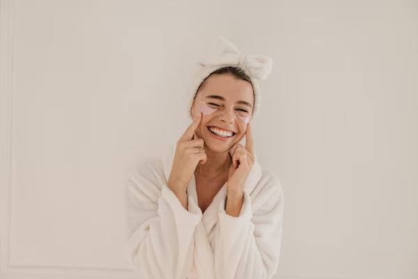 Woman in a spa robe applying under-eye patches